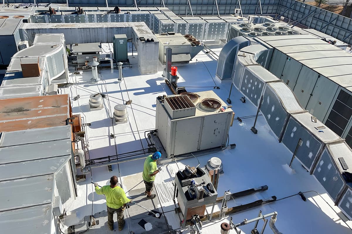 Cook Coatings crew applying a roof coating during a scheduled maintenance visit