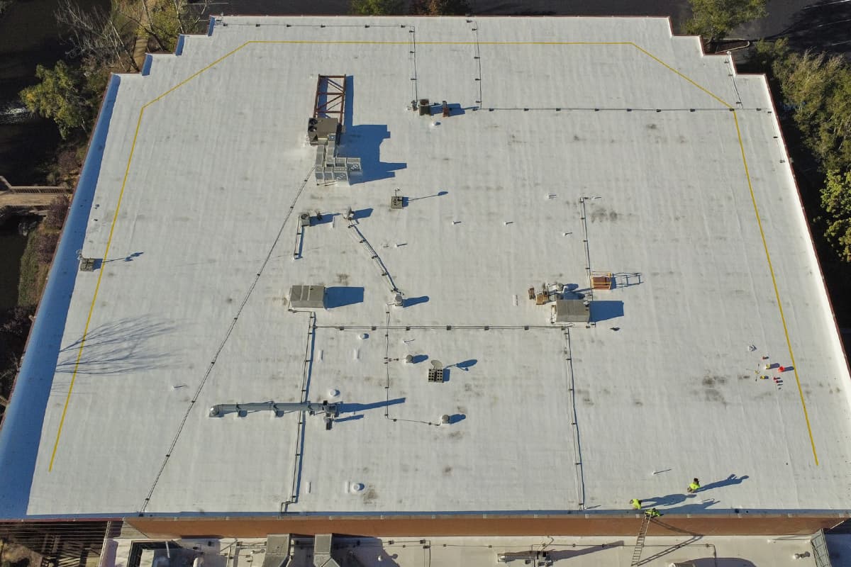 Crew applying a spray foam roof coating system, aerial view